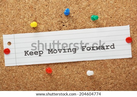 The phrase Keep Moving Forward typed on a piece of paper and pinned to a cork notice board