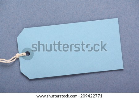 Blank blue luggage or gift tag on a complimentary blue paper background with copy space
