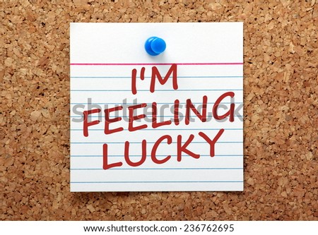 The phrase I'm Feeling Lucky written in red ink on a square index card pinned to a cork notice board