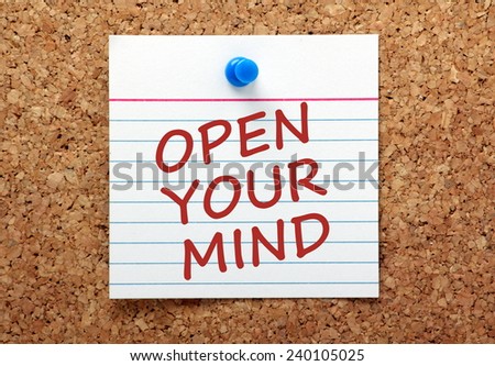 The phrase Open Your Mind written in red ink on a lined note card pinned to a cork notice board
