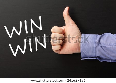 Male hand wearing  business shirt giving a thumbs up gesture to the phrase Win Win written on a blackboard