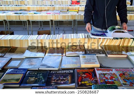 London, England - January 24, 2015: Person browsing the books for sale at the Southbank Centre Book Market in London, England. Located beneath the Waterloo Bridge the market is open all year round.