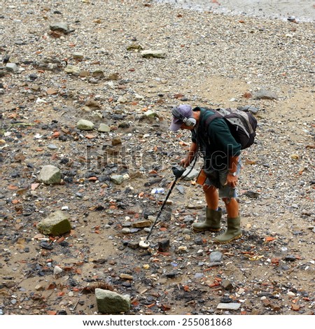 London,England - September 22, 2009: Man using a metal detector at low tide on the River Thames in London, England. A permit is required and any finds must be reported by law under the Treasure Act.