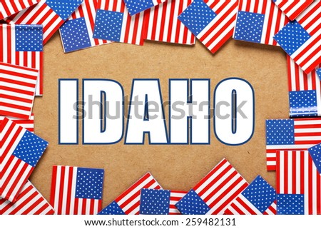 Miniature flags of the United States of America form a border on brown card around the name of the state of Idaho