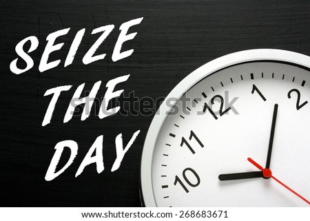The phrase Seize The Day in white text on a blackboard next to a modern wall clock displaying the time