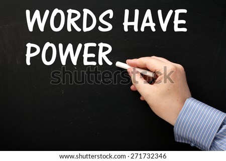 Male hand wearing a business shirt writing the phrase Words Have Power on a blackboard in white text