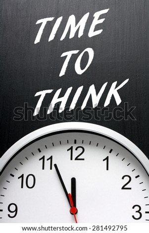 The phrase Time To Think in white text on a blackboard above a modern wall clock with the hands pointing towards midnight or twelve