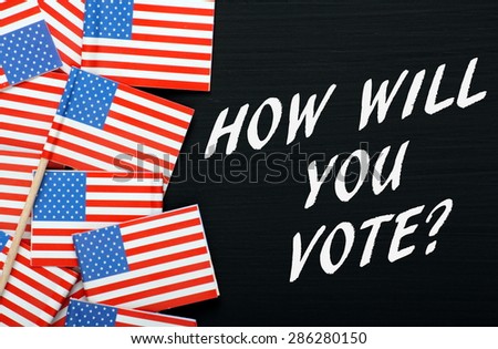 The question How Will You Vote in white text on a blackboard next to flags of the United States of America