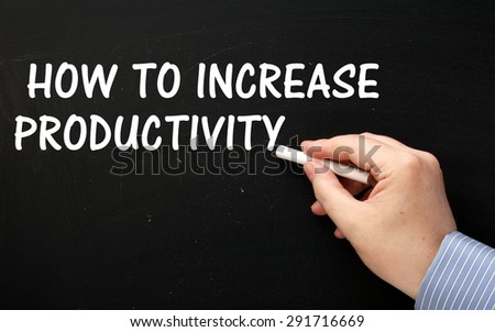 Male hand wearing a business shirt writing the phrase How to Increase Productivity on a blackboard