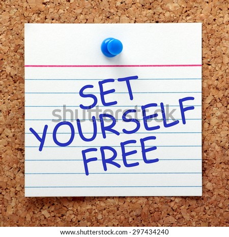 The phrase Set Yourself Free in blue text on an index card pinned to a cork notice board as  a reminder