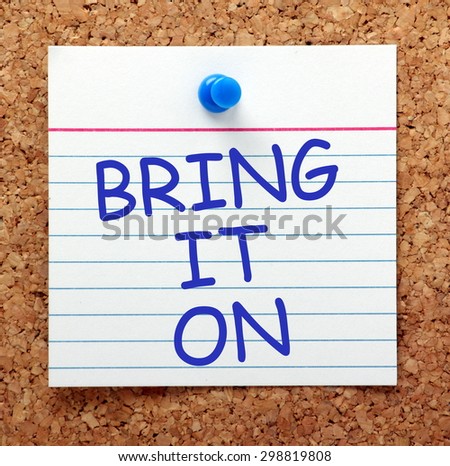 The phrase Bring It On in blue text on an index card pinned to a cork notice board as a reminder
