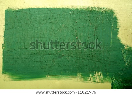 A plastic wall with a green painted patch that has been scratched.