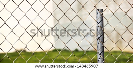 Selective focus is on the fence in the foreground. Also, it is an empty lot behind the metal fence.