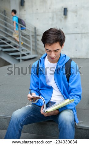 portrait of male college student sitting holding book at college