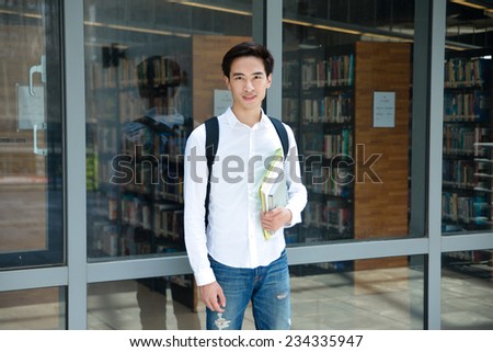 Portrait of college student standing holding book at college