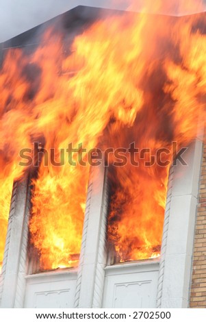 Flames shooting out of the windows of a burning apartment