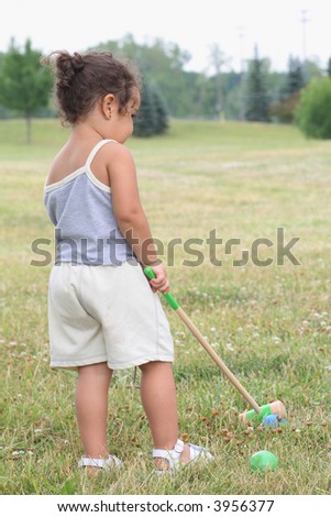 Toddler playing a gamer of croquet on a sunny summer day