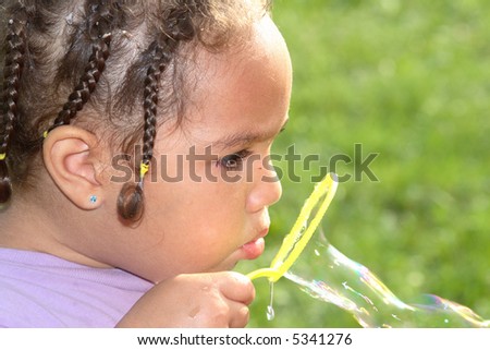 A close-up of a girl blowing bubbles with her yellow bubble wand