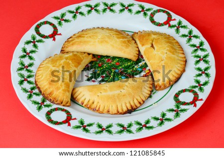 Fresh fried apricot pies (baked) on Christmas Plate decorated with tree and holly against red background.  Referred to as Fried Pies, these are actually baked in oven.