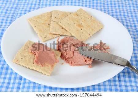 Seriously unhealthy snack of processed potted meat on saltine crackers.