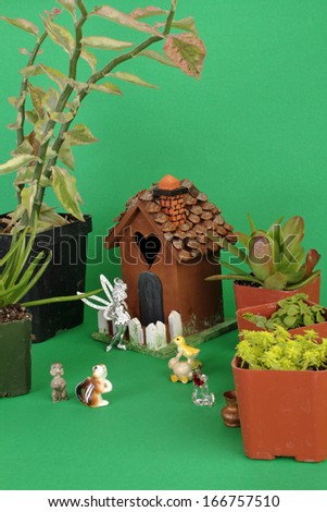 One of series of images on how to create Fairy Garden.  small succulent plants, painted birdhouse; fairy with wings; and tiny ceramic animals, bird; squirrel; dog; rabbit.  Vertical with copy space