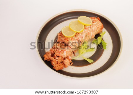 Salmon Roll stuffed with lobster and garnished with lemon and celery.