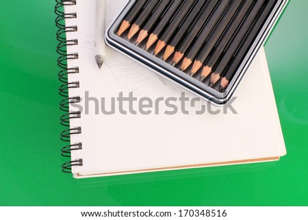 Set of graphite sketching pencils on spiral sketch pad with blending stump.