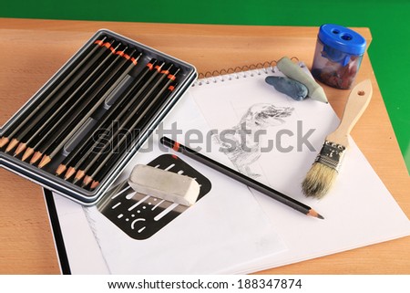Art supplies on drawing pad with image of dachshund dog.  Guidelines and shading utensils with brush and erasers.