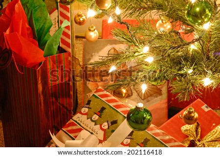 Bright lights and decorative bulbs on Christmas Tree surrounded by wrapped gifts.  Special effect with star flare glistening.