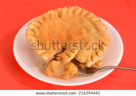 Personal-size Microwave Apple Pie on white saucer against bright red background.