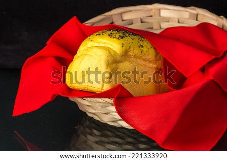 Loaf of Poppy seed bread in basket wrapped in red cloth reflecting in glass tabletop.  Kitchen Art Still Life