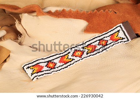 Native American pattern in black, orange, yellow and white beaded bracelet on scraps of leather and rawhide.