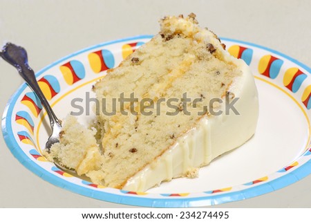 Taking bit from large slice of elegant Two-Layer Italian Cream Cake on paper plate against neutral background.