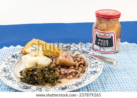 LLANO, TEXAS-DEC 15, 2014:  Focus is on jar of Hormel Pickled Pigs Feet with large plate of ethnic food in foreground.