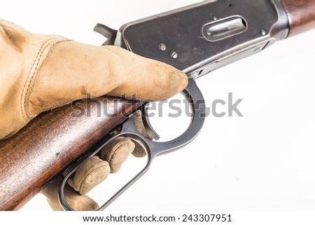 Classic lever action rifle as seen in most western movies in gloved hand against white background.