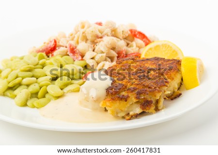Fillet of Cod breaded in crumbs and spices and baked to golden brown on plate with lima beans and pasta salad.  White background with copy space.