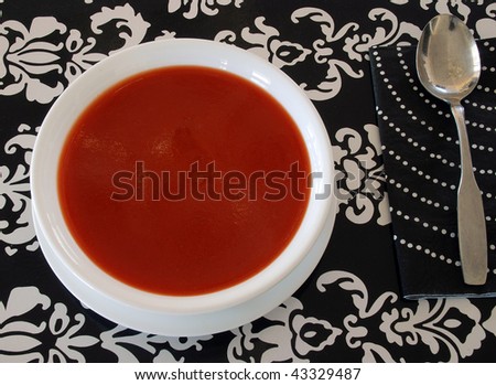 Bowl of Hot Tomato soup in white bowl isolated on black and white background.