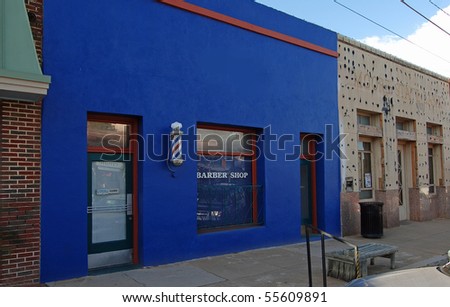 Small town barber shop in blue building with the traditional red, white and blue candy-striped  barber pole.