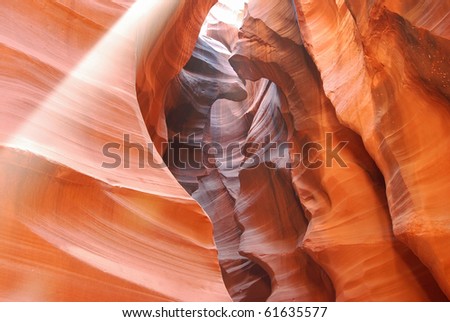 Bright shaft of light streaking in from above in the cool shadows of Antelope Canyon, a world famous tourist sight on Navajo Tribal Lands near Page, Arizona.