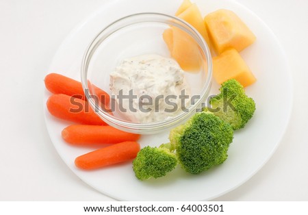 Small veggie plate of baby carrots, broccoli, cantaloupe and garlic dip.  White plate on white background. Clean and simple.