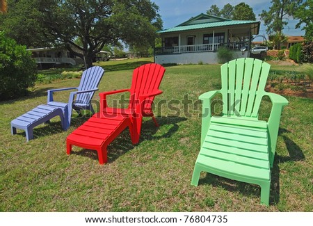 Brightly colored lawn furniture with small summer cottage in background.