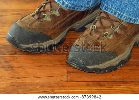Heavy duty, steel toed work boots with denim jeans on rustic old floor.