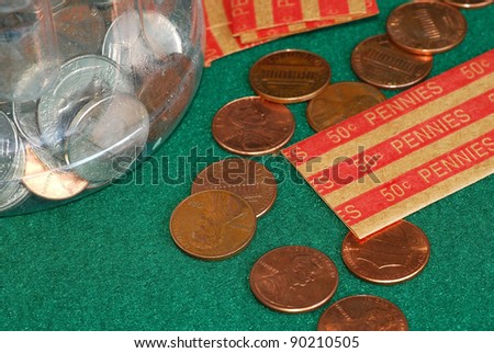 Pennies on green felt background being counted and rolled to emphasize the importance of saving.