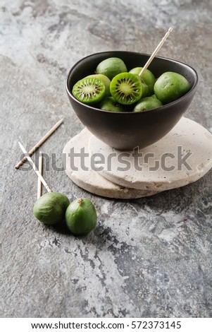 New Zealand exotic food. Berry nergi, or small kiwi. In a brown plate. Grey stone background Photo stock © 