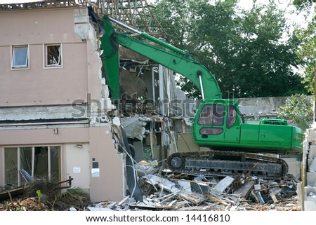 Medium weight shovel tearing down a building in preparation for construction.