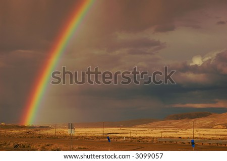 Rainbow emerging from the town of Elko, Nevada, in a rain storm over farmland and desert