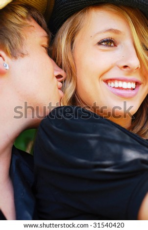 Teenage boy whispering secrets in his girlfriend\'s ear