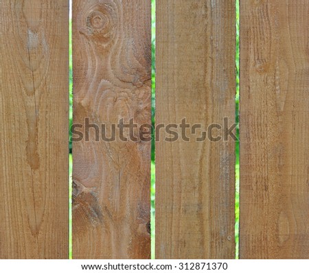 Wooden Fence from Pine Boards with a View to the Green Plants through the Gap