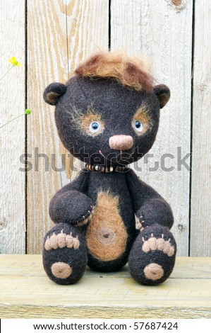 Handmade, the sewed toys: teddy-bear Mocca on a wooden bench against wooden boards