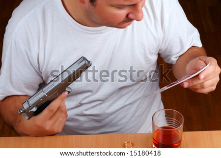 Sad man looking into the photo of a lost love (or a child) while consuming alcohol and wanting to commit suicide (conceptual)